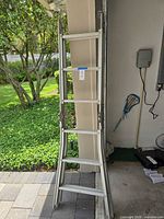 full view of folded aluminum ladder leaning against wall