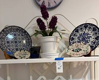 Full lot view showing plates, planter with flowers, plaques, and stand