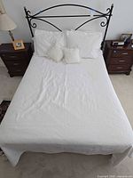 Full view of assembled queen bed with metal headboard, coverlet, pillows