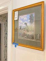 Gold wood framed print with green mat hanging on wall
