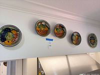 Five plates mounted on wall showing fruit designs and sizing