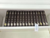 Sixteen brown slipcase volumes lined on shelf