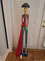Full view tall painted wood matador figurine with red cape