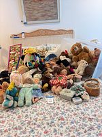 Group shot of all dolls, plush animals, boxes, and baskets on bed
