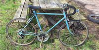 Blue drop-bar road bicycle leaning against picnic table