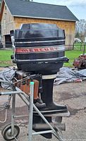 Front and side view of Mercury outboard motor mounted on wheeled stand