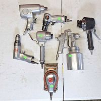 Group of seven pneumatic tools laid out on table