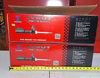 Two boxed FCS Auto struts stacked with tape measure showing 23-inch length