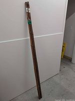 Full view of three bamboo poles leaning against wall