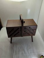 Closed sewing box front view showing handle, legs, missing knob