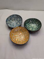 Top view of three coconut shell bowls showing coloured mosaic interiors