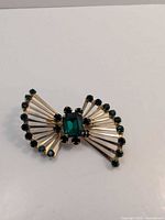 Front view of Coro gold-tone bow brooch with green stones