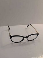 Front three-quarter view of black and gold eyeglass frame