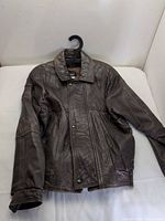 Front view of brown leather jacket on hanger