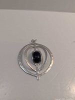 Front view of pendant showing hammered concentric ovals and black cabochon