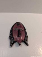 Front view of carved stone mask pendant