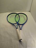 Two blue Head Conquest rackets overlapped on surface