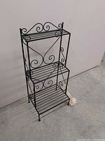 Full view of black wrought iron three-tier plant stand
