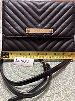 Front view showing chevron quilt design, logo plaque, strap and width measurement