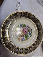 Front view showing floral centre and black-gold border with beaded rim