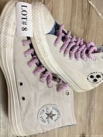 Side view of both high-top sneakers showing canvas uppers, laces, and ankle patch