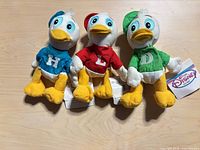 Front view of all three Disney plush toys showing colors and tags