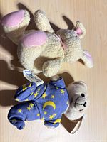 Front view of both plush bears, one in blue pajamas, one tan with pink accents