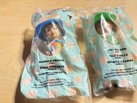 Front view of both sealed dolls in turquoise polka-dot bags