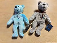 Light blue and gray plush teddy bears with swing tags visible