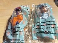 Front view of both sealed dolls in bags showing costumes