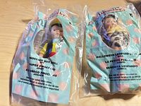 Front view of both sealed dolls showing packaging text and characters