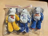 Front view of all three collegiate plush bears in sealed bag