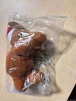 Brown plush toy with Santa hat inside clear plastic bag