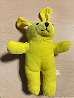 front view of yellow plush toy showing embroidered face and ears