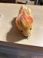 Front view of yellow and orange plush cat toy showing mane, face and loop