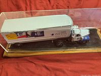 Full view of USPS die-cast truck and trailer under acrylic cover on wood base