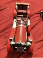 Top view of red tin model car showing hood, fenders, grille, spare tire, and interior