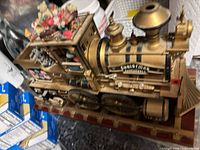 Side view of gold resin Christmas locomotive on red base with Crosstimes Express plaque and elf-filled cab