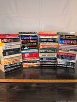 Three stacks of assorted paperback books showing variety and quantity