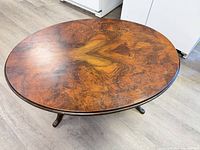 Top view of oval burl veneer table showing grain and finish wear