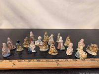 Group shot of all 18 miniature figurines with ruler for scale