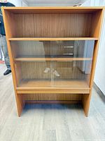 front view showing cabinet structure, sliding glass doors, shelves, teak-tone finish