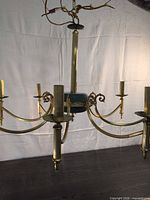 Full view of six-arm brass chandelier with green accent and candle sockets