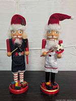 Front view of both Santa nutcrackers showing props and bases