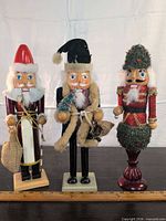 Front view of all three wood nutcrackers on tabletop with ruler for scale