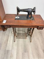 Full view of Singer sewing machine in wood cabinet on cast-iron treadle base