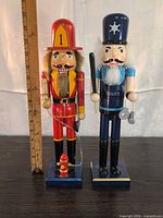 Front view of firefighter and police nutcracker figurines with ruler indicating height