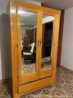 front view of closed armoire showing mirrored doors and bottom drawer