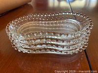 Stack of four clear glass plates showing hobnail edge profile