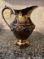 Full view of silver-plated pitcher on granite countertop